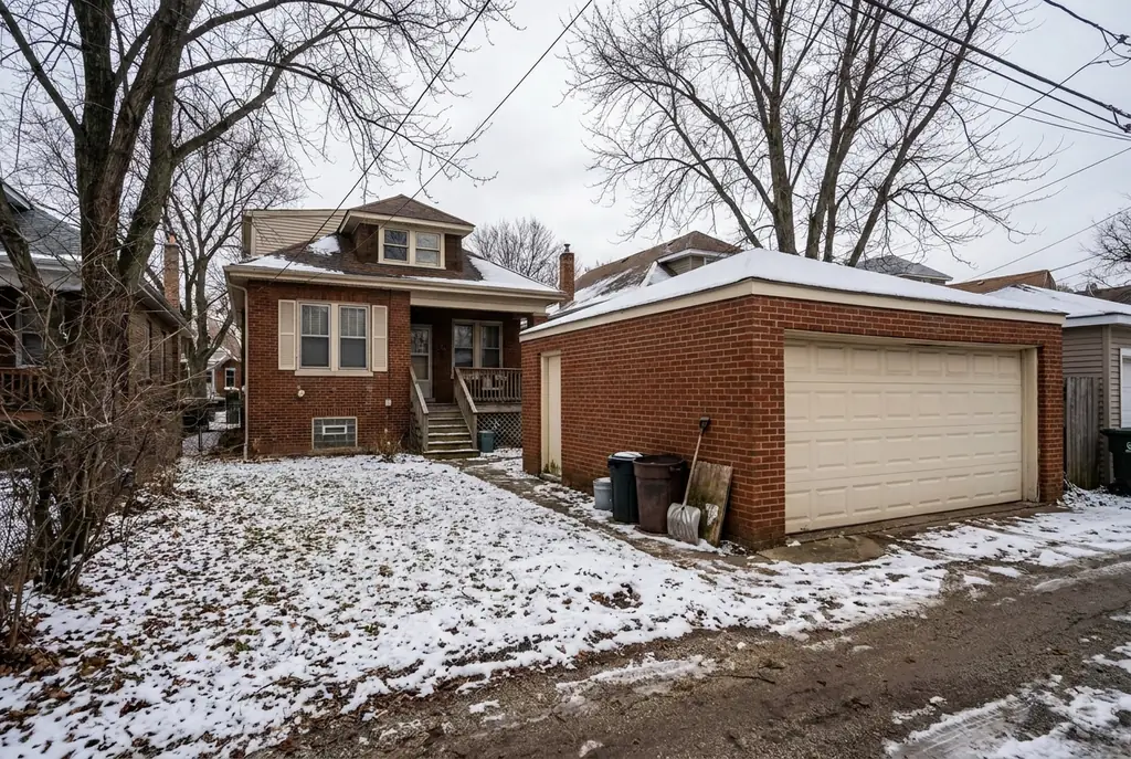Detached brick garage behind a Chicago bungalow, facing the alley, with a raised-panel steel door.