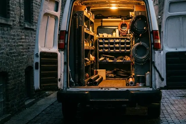 Garage door service van in a Chicago alley with its rear doors open, stocked with torsion springs, cables, rollers and parts bins.